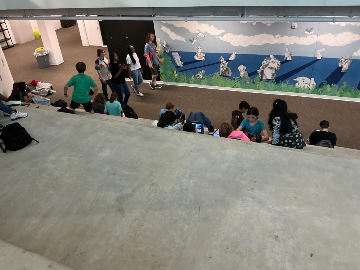H-B students sitting on stone stairs while on their iPads.
